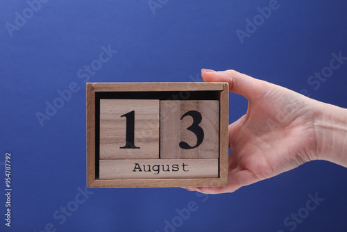 Wallpaper Mural Female Hand holding wooden block calendar with the date August 13 on a blue background Torontodigital.ca