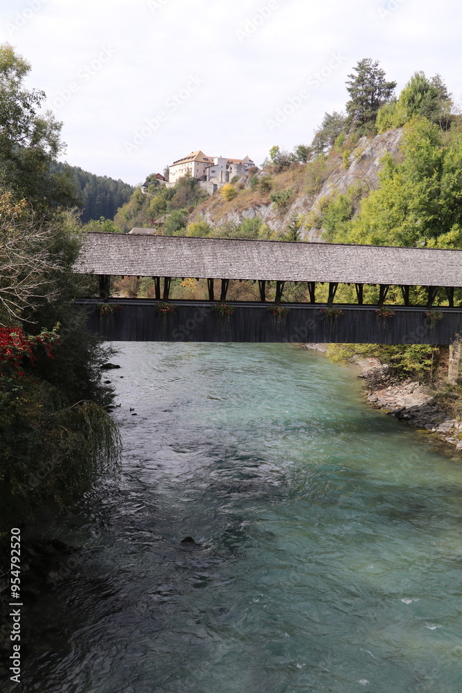 covered wooden bridge over a mountain river with in the distance a medieval castle on the top of the cliff covered wooden bridge over a mountain river with in the distance a medieval castle on the top of the cliff