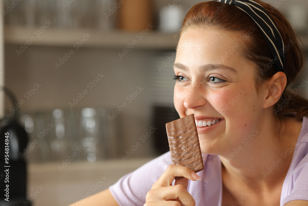 Happy woman in the kitchen holding cookie Happy woman in the kitchen holding cookie