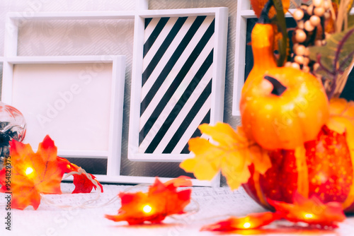 Blank photo frames with pumpkins and a garland of maple leaves on the dresser in room, closeup