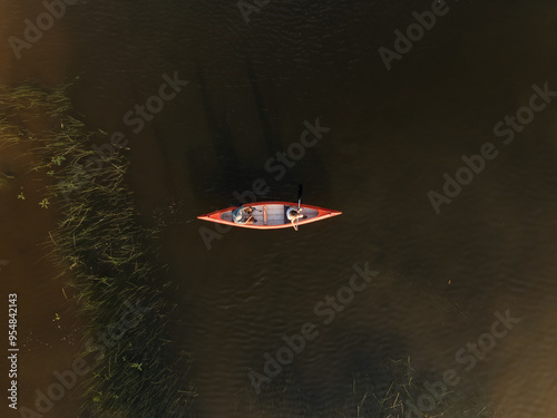 Active couple taking a canoe ride across the beautiful mountain lake, enjoying summer nature on a lakeshore vacation, aerial shot. photo