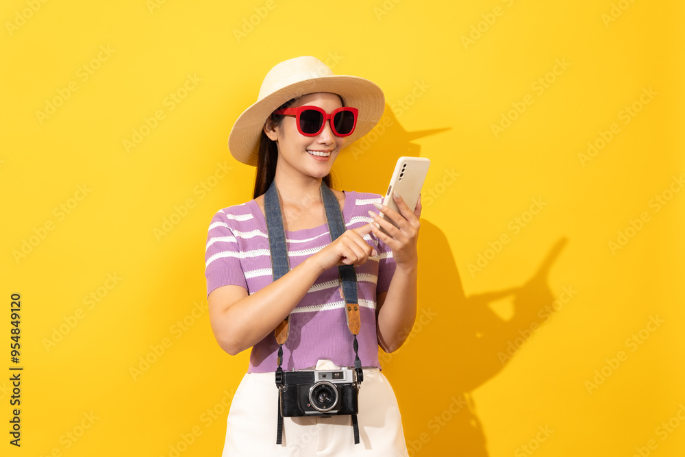 Smiling Asian woman with luggage and a rubber ring, wearing t-shirts featuring coconut tree flowers, vibrant yellow backdrop, summer. Smiling Asian woman with luggage and a rubber ring, wearing t-shirts featuring coconut tree flowers, vibrant yellow backdrop, summer.