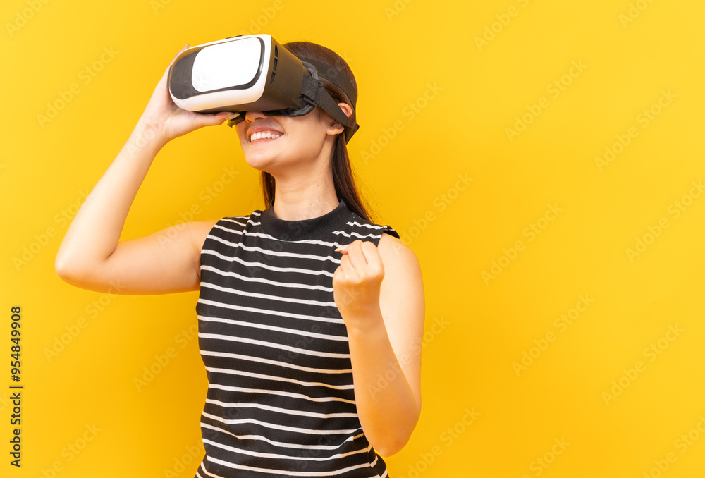 Asian young woman playing video games using mobile with headphones on yellow background isolated. Asian young woman playing video games using mobile with headphones on yellow background isolated.