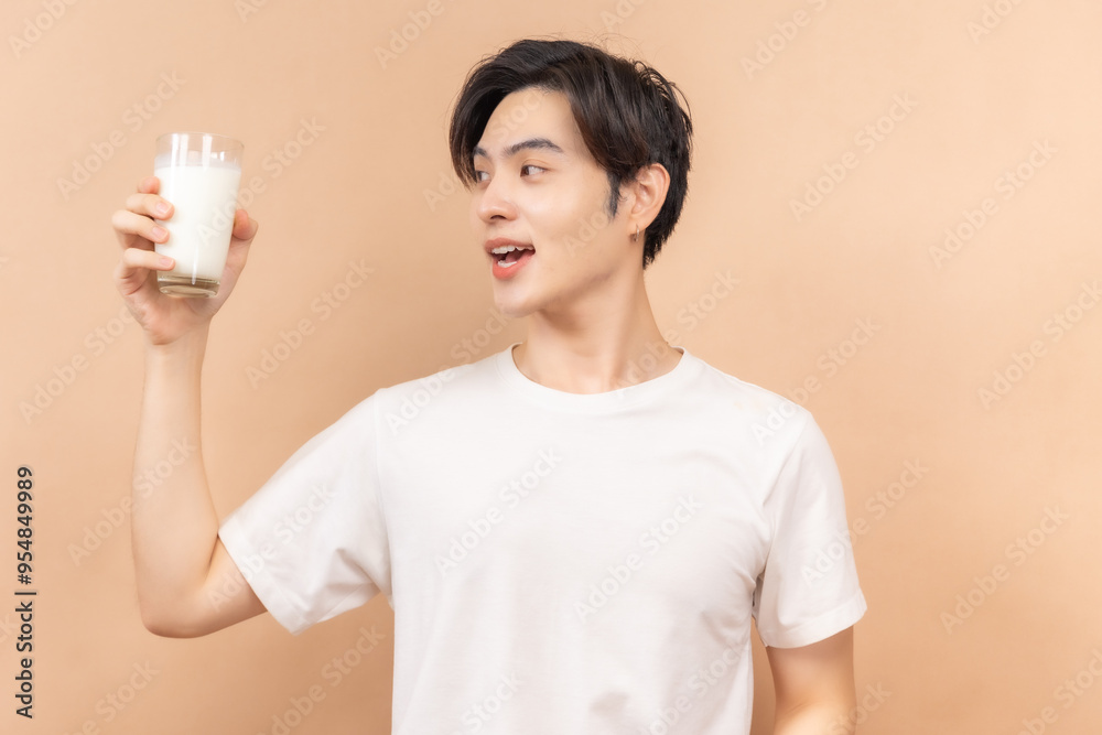 A happy asian people in white shirts, holding glasses of milk and a bowl of salad, against a beige background. A happy asian people in white shirts, holding glasses of milk and a bowl of salad, against a beige background.