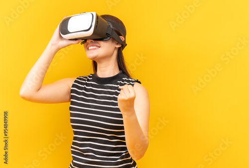 Asian young woman playing video games using mobile with headphones on yellow background isolated.