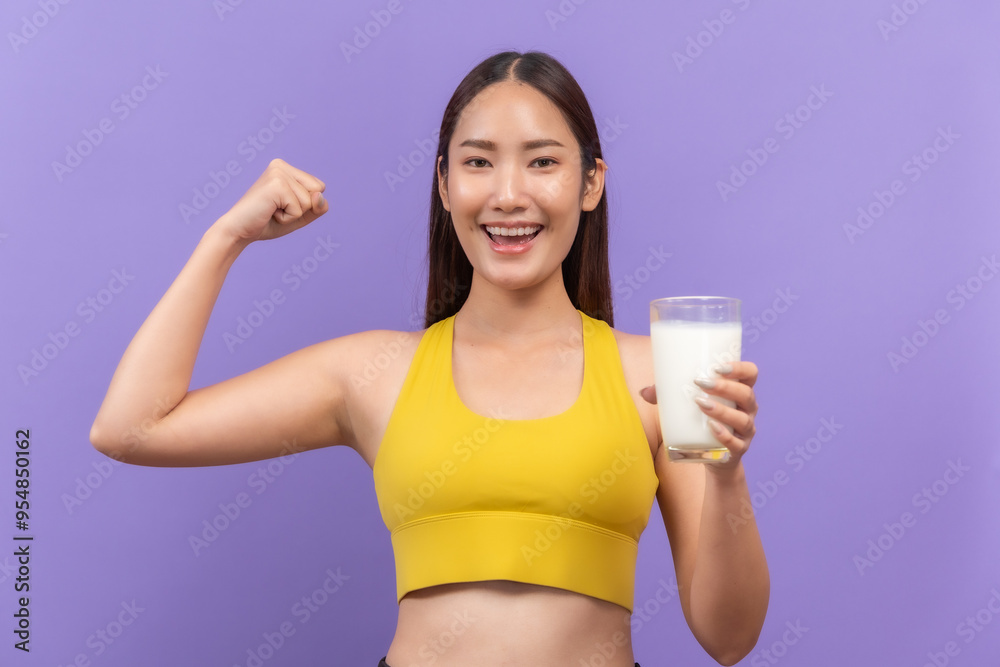 Young woman in a yellow sports bra, joyfully drinking a glass of milk, with a purple backdrop Young woman in a yellow sports bra, joyfully drinking a glass of milk, with a purple backdrop