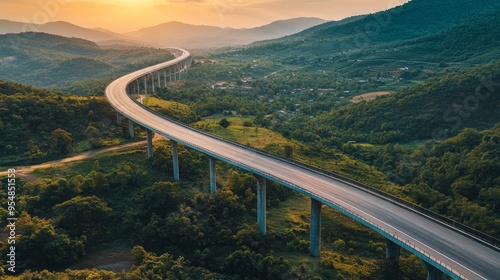 An overhead picture of a motorway bridge that connects towns at dusk, spanning a valley with verdant hills and forests as part of infrastructure development