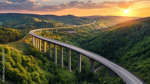An overhead picture of a motorway bridge that connects towns at dusk, spanning a valley with verdant hills and forests as part of infrastructure development