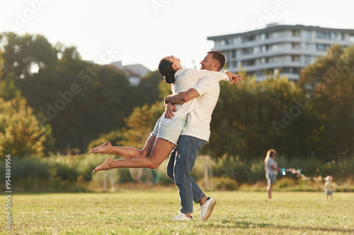 Closeness, embracing. Mother and father are with son outdoors on the field