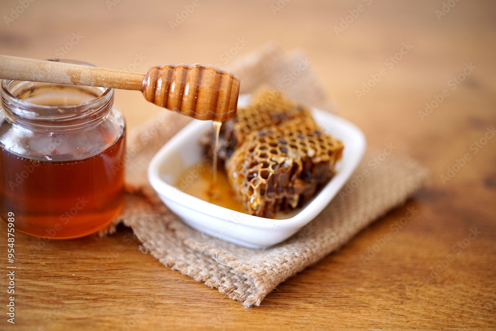 Honey jar, dipper and honeycomb on wooden table