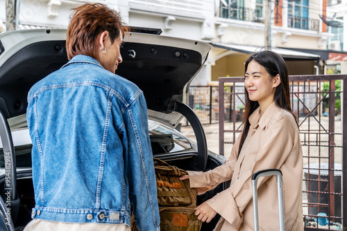 Couple young asian man and woman tourist puts his backpack suitcase package luggage in the car boot trunk. Preparing for vacation. Loading a car for a sstkroadtrip. Travel. Summer adventure photo