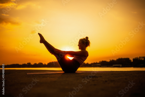Tableau sur toile Woman exercising pilates in sunset. Teaser exercise.