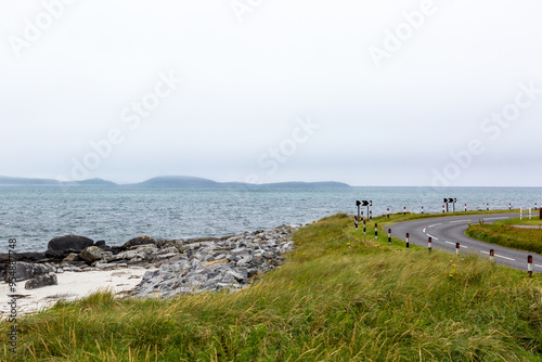 Landscape view of a main road in South Uist following the coast line with a small beach just to the left on a cloudy day photo