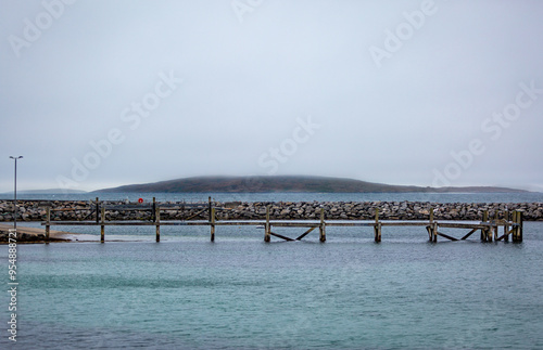 Eriskay ferry terminal on a cloudy summers day empty, Image shows a blue Atlantic ocean with a wooden pier used for mooring up docking ferries photo