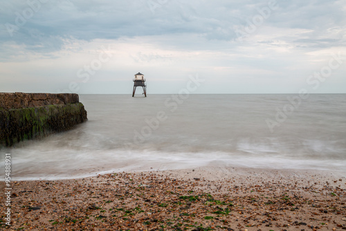 Naklejka Lighthouse in the sea long exposure, Dovercourt lighthouse at high tide built in 1863 and discontinued in 1917 and restored in 1980 the lighthouse is still a iconic sight on a cloudy evening 