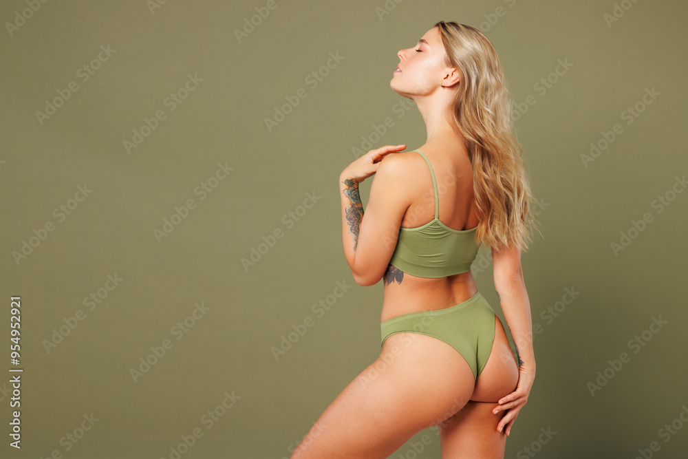 Back rear side view young lady woman with slim skinny body perfect skin wear top bra lingerie stand put hand on thigh posing close eyes isolated on plain green background. Lifestyle diet fit concept. Back rear side view young lady woman with slim skinny body perfect skin wear top bra lingerie stand put hand on thigh posing close eyes isolated on plain green background. Lifestyle diet fit concept.