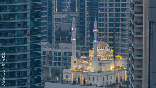 Al Raheem mosque between skyscrapers day to night timelapse on the marina walk in Dubai Marina, Dubai, UAE. photo