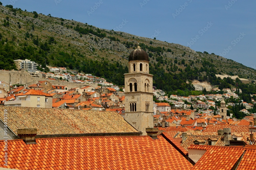 Obraz premium Dubrovnik's historic charm, with its iconic terracotta rooftops and church bell tower set against lush hills. A UNESCO World Heritage site, the Old Town blends history, culture, and natural beauty.