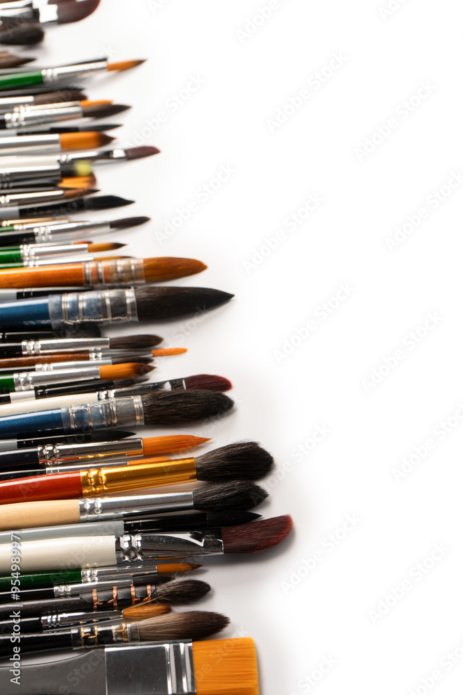 Fototapeta premium Mix of paint brushes in a row isolated on a white background. Top view.