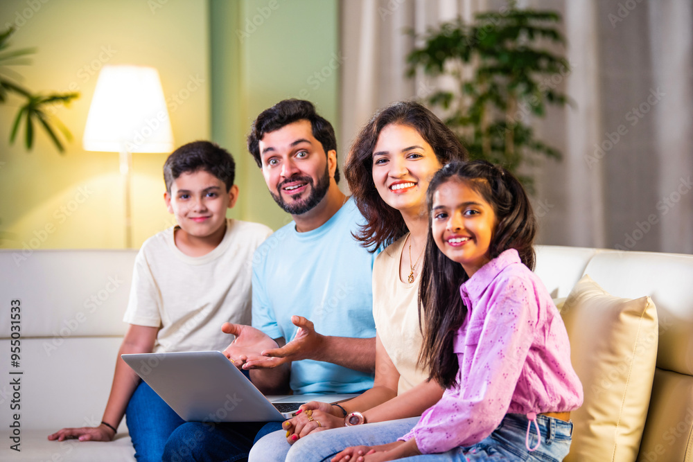 Indian family of four on sofa enjoying quality time with tablet or laptop, blending fun learning Indian family of four on sofa enjoying quality time with tablet or laptop, blending fun learning