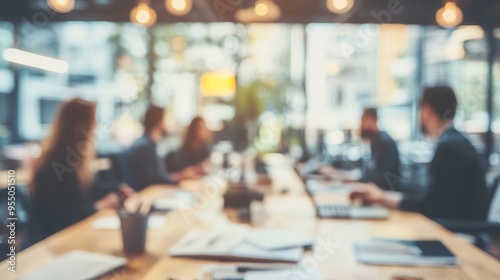 Blurred silhouettes of business professionals gathered around a long table in a modern office space, conveying a sense of collaboration and teamwork.