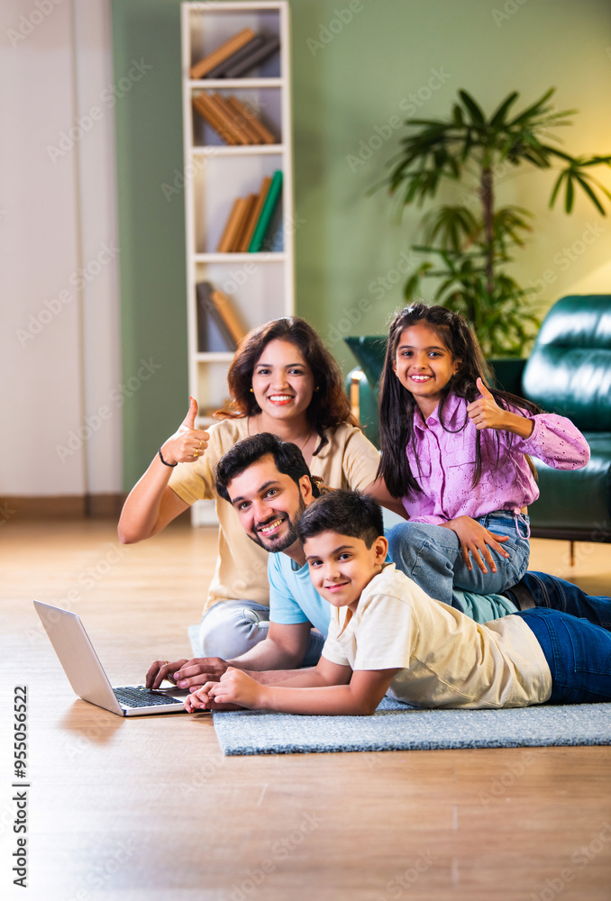 Indian family of four on sofa enjoying quality time with tablet or laptop, blending fun learning Indian family of four on sofa enjoying quality time with tablet or laptop, blending fun learning