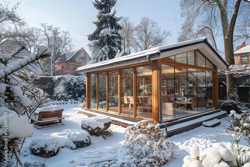 Snow-covered garden with sunroom and glass walls, wooden door leading to a sunny backyard in winter, Germany. photo