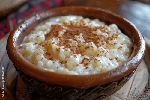 A serving of rizogalo, a creamy rice pudding sprinkled with cinnamon, served in a rustic ceramic bowl.