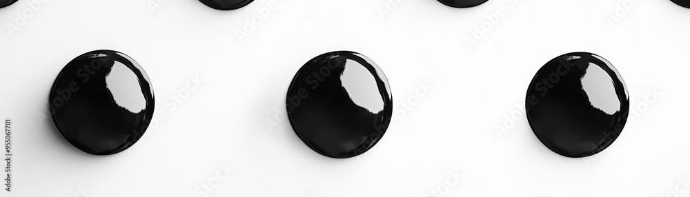 A close-up of glossy black droplets arranged in a neat pattern on a white surface, creating a striking visual contrast. A close-up of glossy black droplets arranged in a neat pattern on a white surface, creating a striking visual contrast.