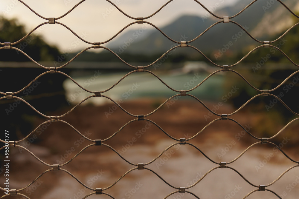 The blured view through metal grid to the mountain blue water lake in the north of italy The blured view through metal grid to the mountain blue water lake in the north of italy