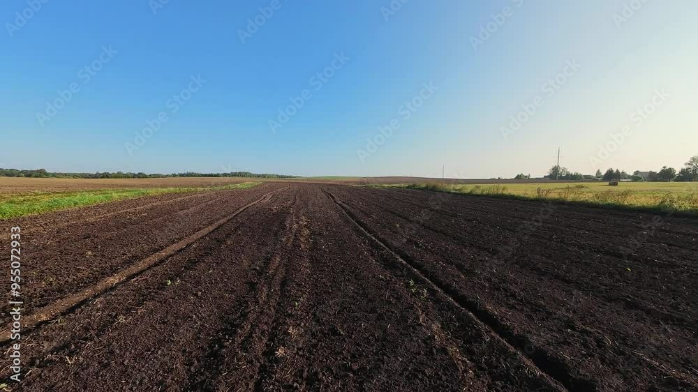 A close aerial shot of a freshly plowed field with rich dark soil under a clear blue sky, highlighting the preparation for the next agricultural cycle. High quality 4k footage