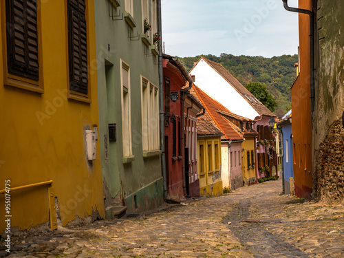 Uphill view on empty Sighisoara street with colorful medieval houses, Romania photo