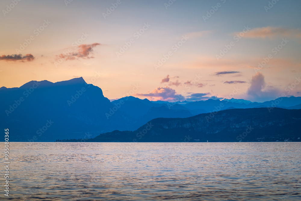 Lake Garda with mountains in background at sunset, view from Lazise town shore, Italy, Europe. Lake Garda with mountains in background at sunset, view from Lazise town shore, Italy, Europe.