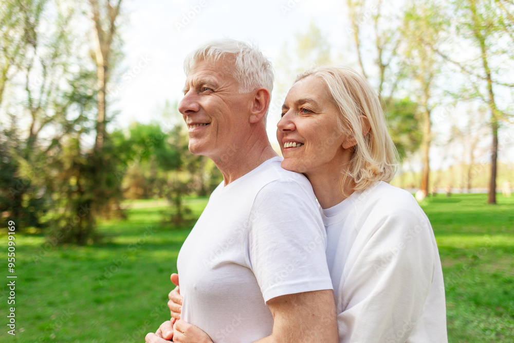 elderly couple of seniors man and woman hugging and smiling in the park outdoors, gray-haired grandparents in white T-shirts in nature elderly couple of seniors man and woman hugging and smiling in the park outdoors, gray-haired grandparents in white T-shirts in nature
