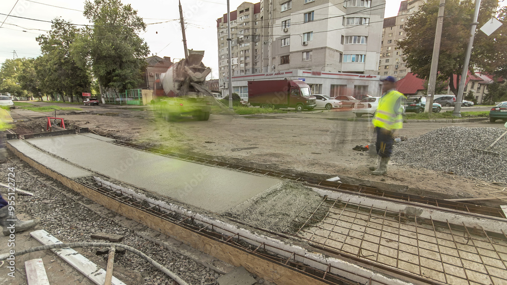 Naklejka premium Concrete works for road construction with many workers and mixer timelapse hyperlapse