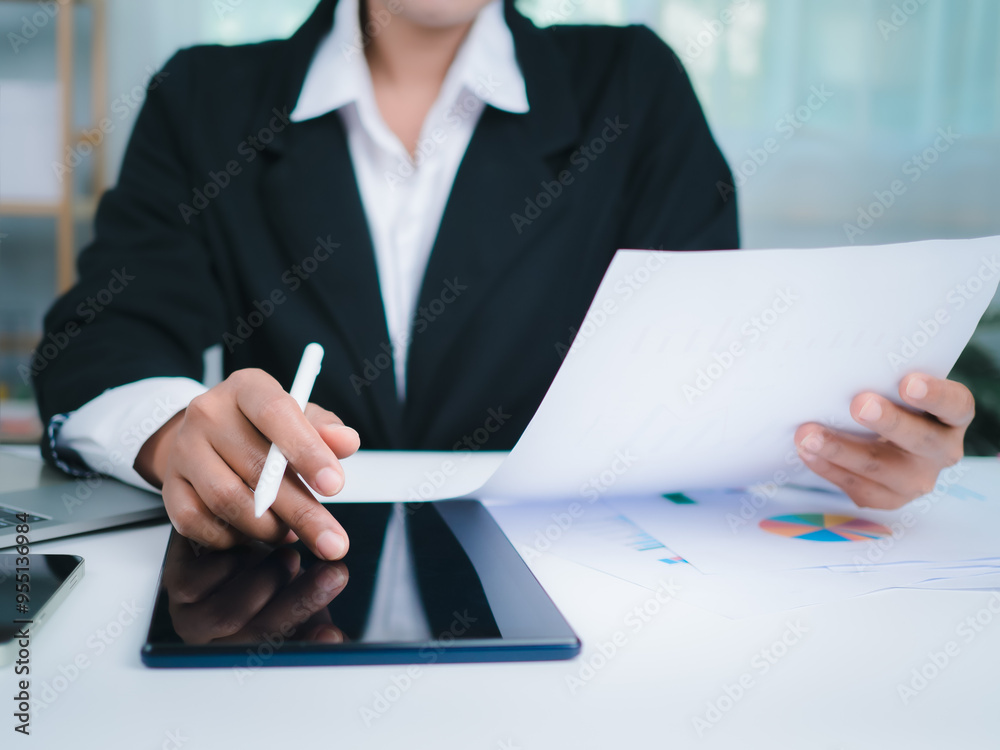 Business Woman in black suit working on tablet, Paper documents and laptop, Hands touch on tablet at office with white background, Online working, Close up, Copy space. Business Woman in black suit working on tablet, Paper documents and laptop, Hands touch on tablet at office with white background, Online working, Close up, Copy space.