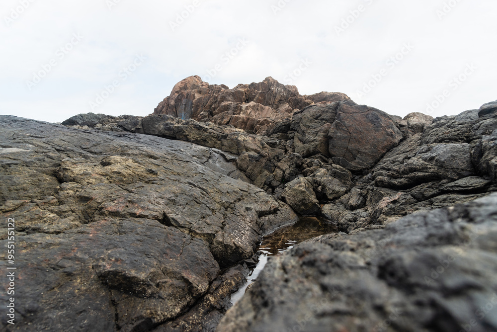 View of dark sea rocks against the ocean and cloudy sky. Preserved nature. View of dark sea rocks against the ocean and cloudy sky. Preserved nature.