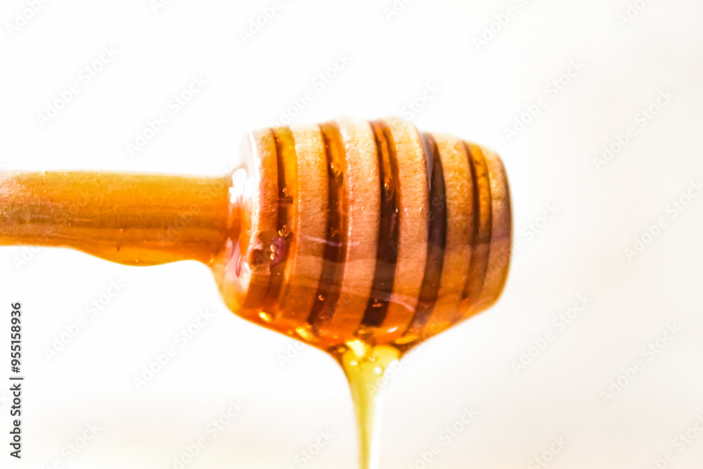 honey dripping from a wooden dipper, isolated on white background honey dripping from a wooden dipper, isolated on white background