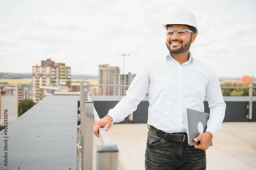 Asian Indian male contractor engineer with hard hat standing in front construction site, inspecting the progress Asian Indian male contractor engineer with hard hat standing in front construction site, inspecting the progress