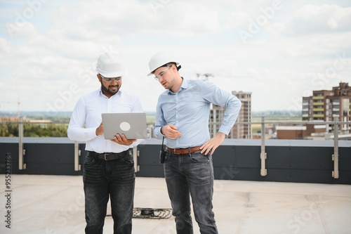 Two multiracial engineer working at site of a large building project. Team of engineer discus at site