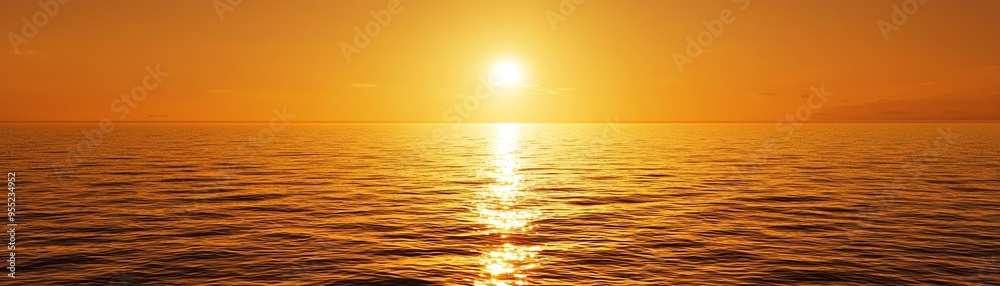 Fototapeta premium A breathtaking sunset over calm waters, creating a warm glow and reflecting hues of orange and gold across the ocean's surface.