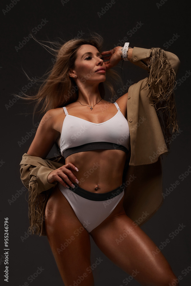 Obraz premium Young fit woman in tracksuit, black background. muscle relief. pumped up buttocks, sportswoman, fitness bikini