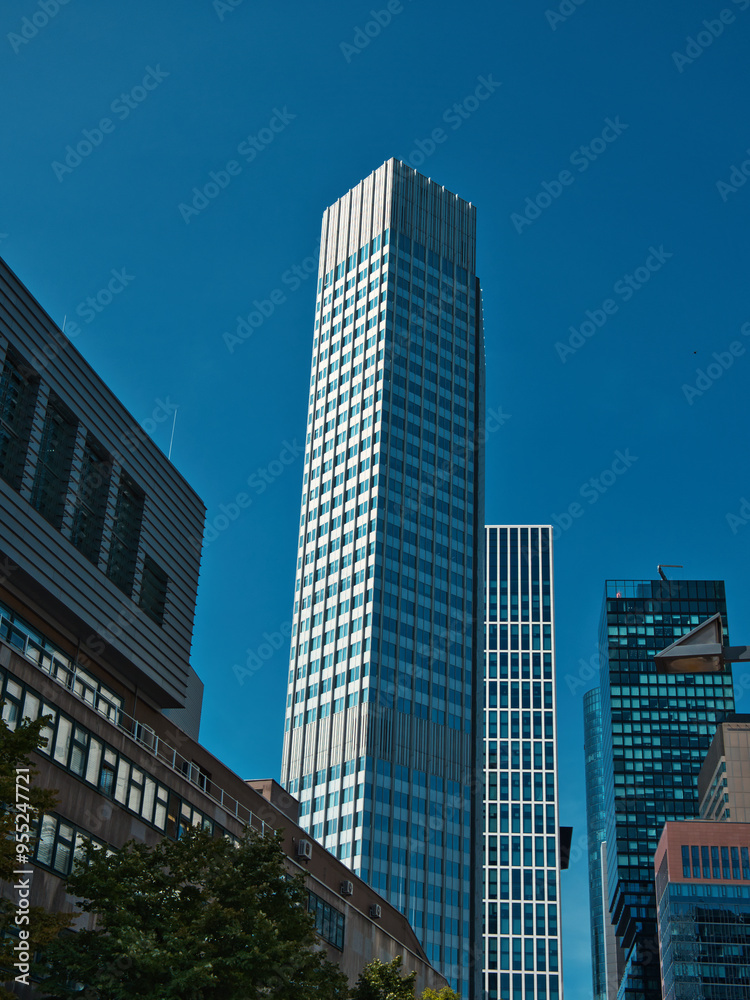 narrow skyscraper in Frankfurt am Main, surrounded by smaller buildings with a clear sky narrow skyscraper in Frankfurt am Main, surrounded by smaller buildings with a clear sky