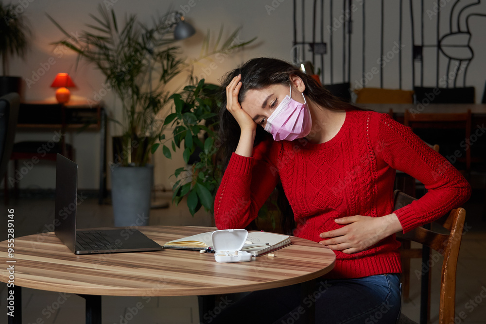 sick woman with pills and thermometer on a table working on a laptop from home on quarantine isolation. sick woman with pills and thermometer on a table working on a laptop from home on quarantine isolation.