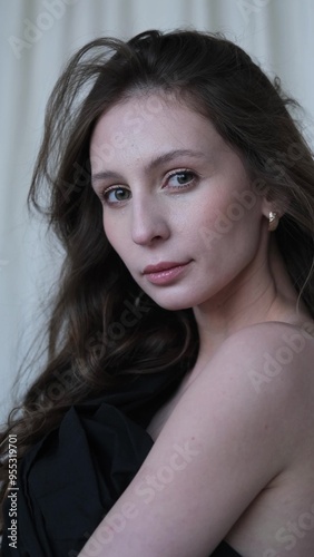 Portrait of a beautiful brunette with long hair on a fabric background in the studio. Beautiful natural woman posing for the camera photo