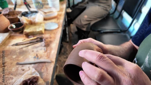 a master potter molds a decorative element onto a mug