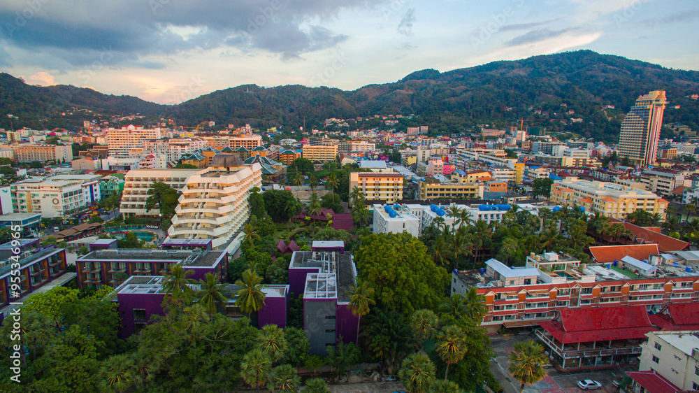 Fototapeta premium A breathtaking aerial view of a coastal bay at sunset, with golden light reflecting on the calm sea and silhouetted hills in the distance. beautiful reflection of the golden sun at Patong Bay Phuket.
