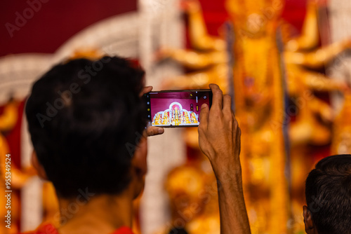 Photography Shubho mahalaya, Hand holding mobile phone and taking photos of Goddess Durga idol at a pandal during navratri