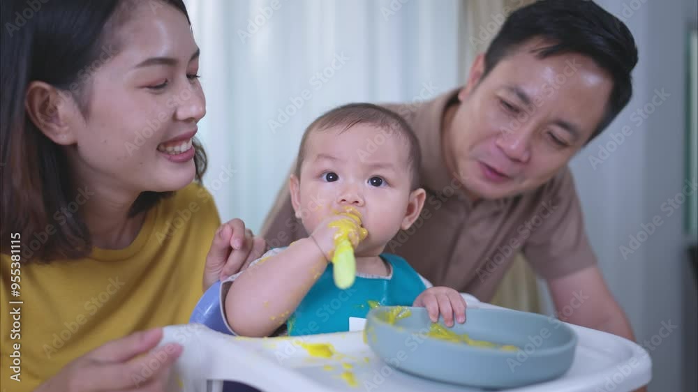 A little child eating his first meal, parents cheer excitedly A little child eating his first meal, parents cheer excitedly
