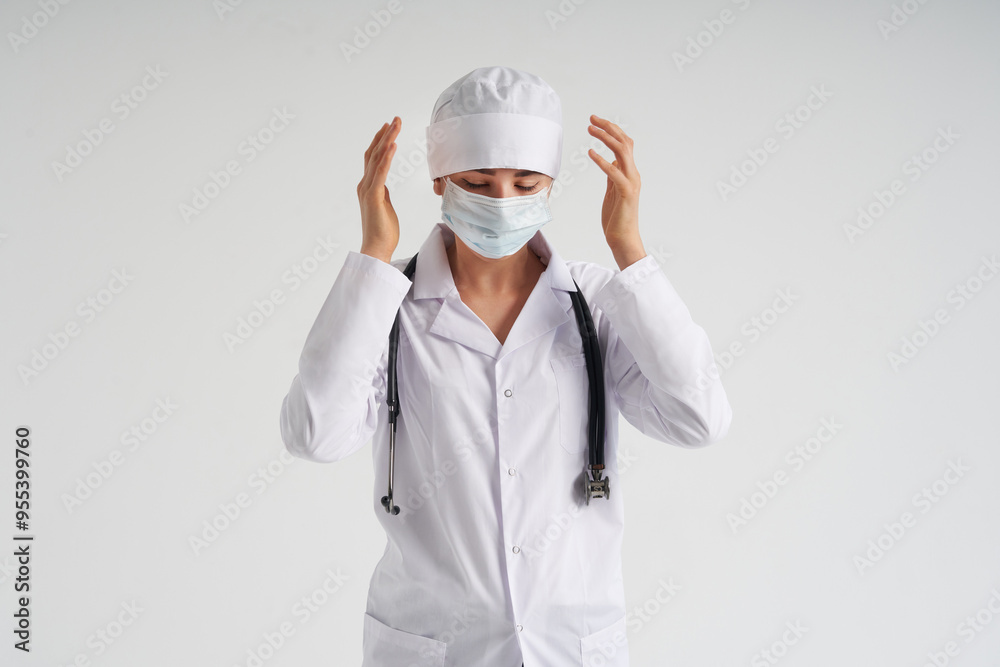 Portrait of young female doctor putting on protective medical face mask on white background, copy space Portrait of young female doctor putting on protective medical face mask on white background, copy space